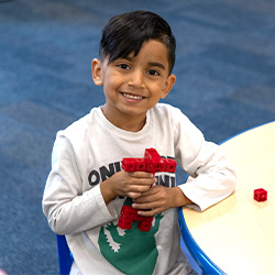 Child playing with red building blocks at La Petite Academy.
