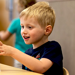 boy at classroom table smiling