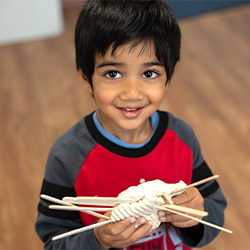 niño pequeño sonriendo y sosteniendo una manualidad