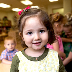 girl in early preschool classroom smiling