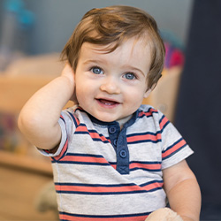 niño sonriendo con la mano sobre la oreja