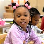 Young child smiling during a classroom activity