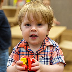 little boy holding toy trucks
