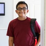 School-age child smiling with a backpack