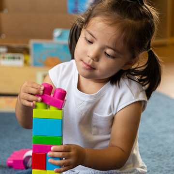 niña pequeña apilando legos